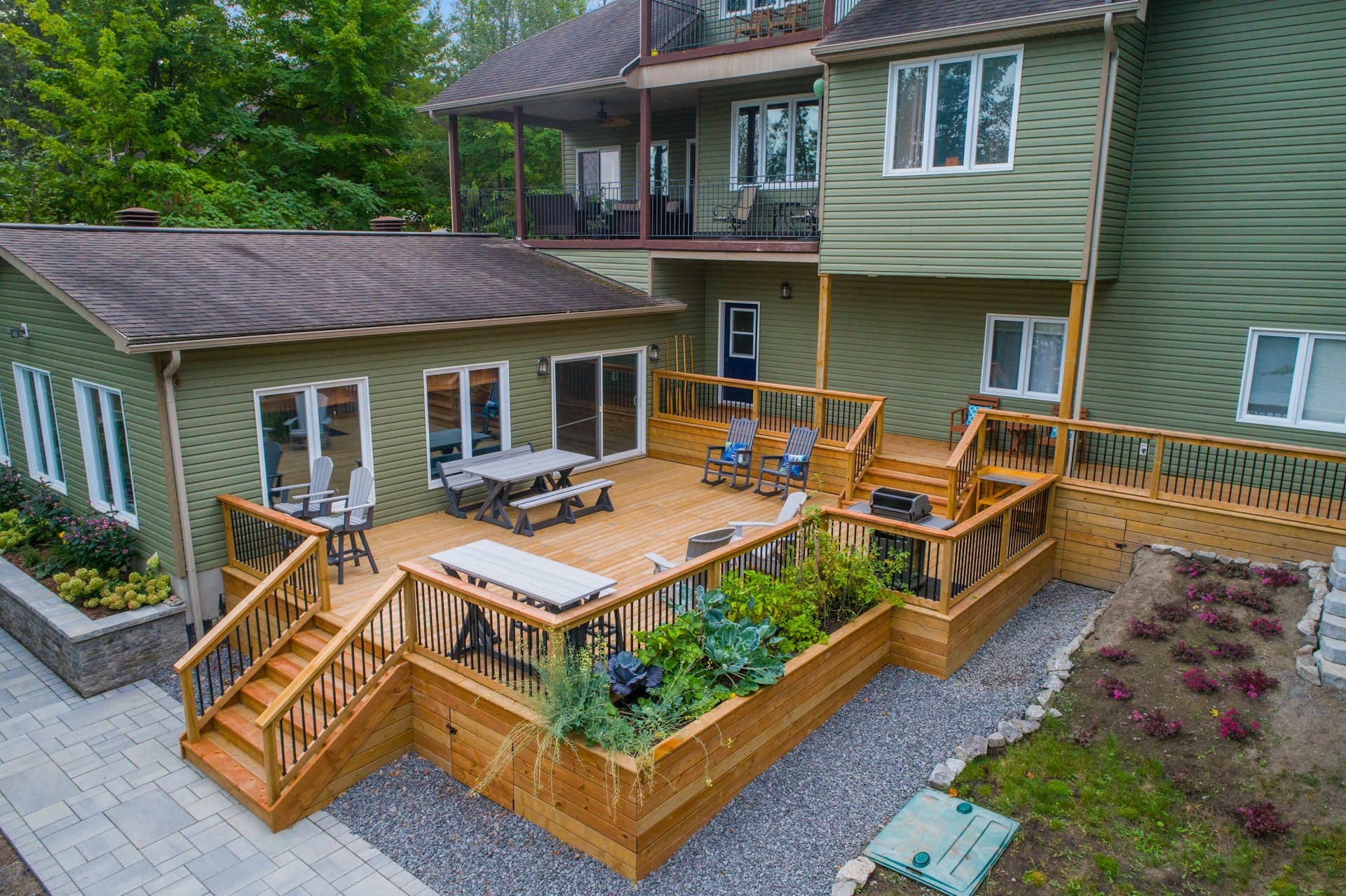 aerial view of a large wooden deck connected to a green hosue.